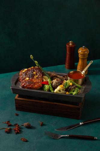a plate of food with meat and vegetables on a table at Peridot Grand Luxury Boutique Hotel in Hanoi