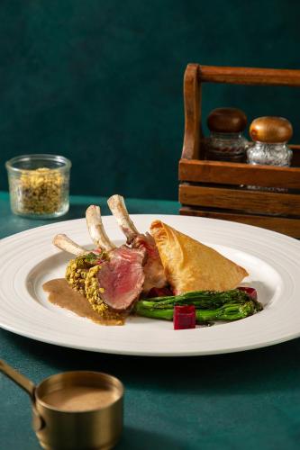 a plate of food with meat and vegetables on a table at Peridot Grand Luxury Boutique Hotel in Hanoi