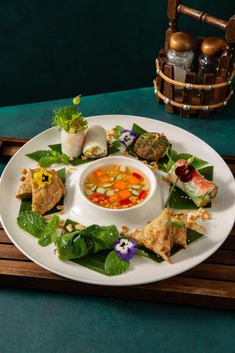 a white plate of food on a wooden table at Peridot Grand Luxury Boutique Hotel in Hanoi