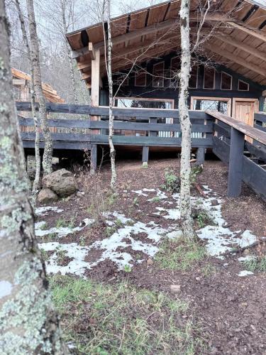 a wooden bench in front of a building with trees at cabañas refugio quillaileo in Santa Bárbara