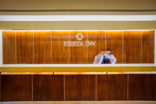 a person is walking past a first act sign on a wall at Fiesta Inn Tuxtla Gutierrez in Tuxtla Gutiérrez