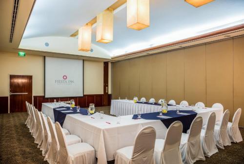 a conference room with tables and chairs and a screen at Fiesta Inn Tuxtla Gutierrez in Tuxtla Gutiérrez