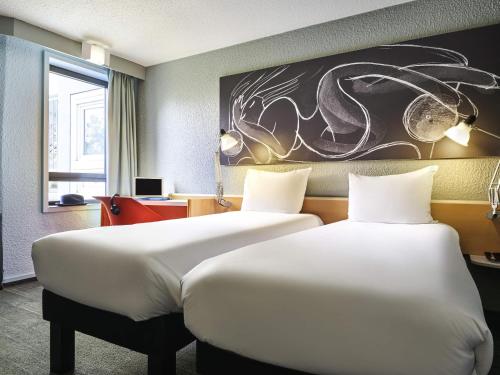 two beds in a room with a painting on the wall at ibis Paris La Villette Cité des Sciences 19ème in Paris