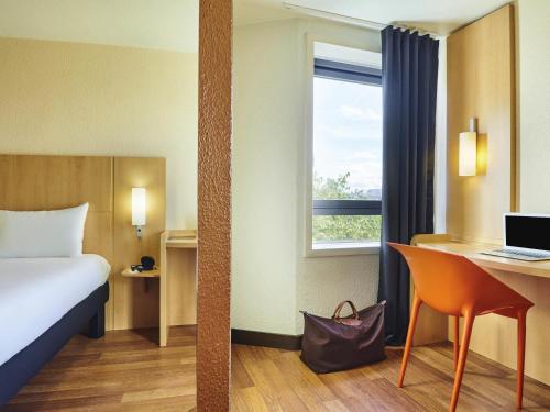 a hotel room with a bed and a desk and a window at ibis Paris La Villette Cité des Sciences 19ème in Paris