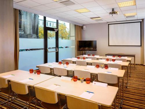 a conference room with tables and chairs and a screen at Ibis Brussels City Centre in Brussels