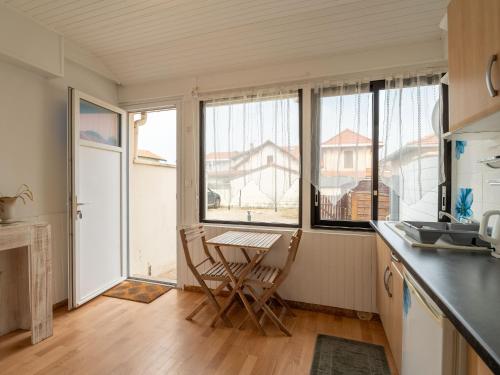 a kitchen with a table and chairs and windows at Appartement pour 3 à Mimizan Plage, à 50m de l'océan avec terrasse et parking, ménage inclus - FR-1-50-123 in Mimizan