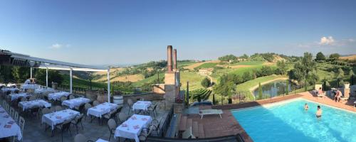 a swimming pool with white tables and chairs at Agriturismo Acetaia Sereni in Marano sul Panaro