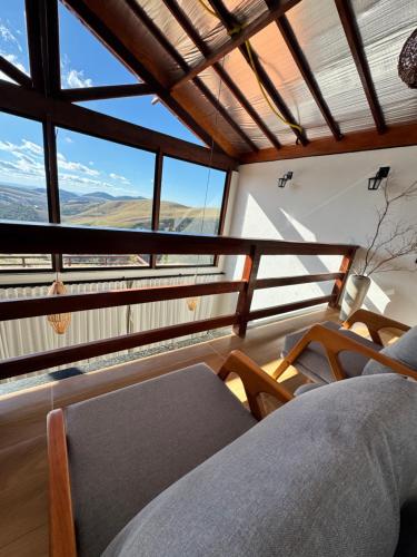 a room with a balcony with a view of the mountains at Chalé Alto do Valle in Paty do Alferes