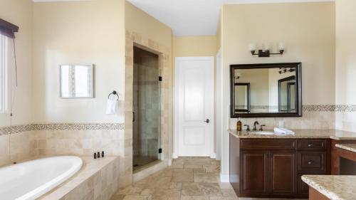 a bathroom with a tub and a sink and a mirror at Palazzo Del Sol By AvantStay Breathtaking Home w Mountain Views Hot Tub in Temecula