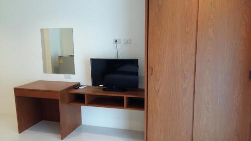 Cette chambre comprend un bureau avec une télévision et un miroir. dans l'établissement DEE DEE Mansion Airport, à Nai Yang Beach