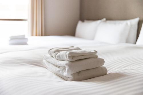 a pile of towels sitting on top of a bed at Eruza HAKATA エルザ博多 in Fukuoka