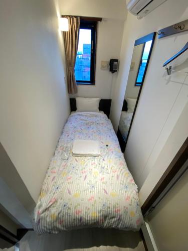 a small bedroom with a bed in a tiny house at Omori Happy Smile Hotel in Wada