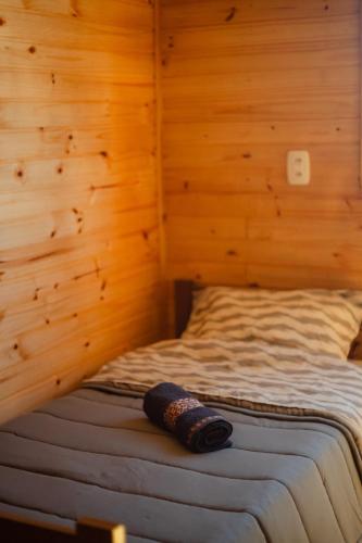 a bed in a room with a wooden wall at Refúgio dos Capitéis in Farroupilha