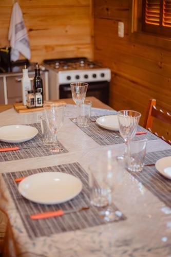 a table with glasses and plates and a stove at Refúgio dos Capitéis in Farroupilha