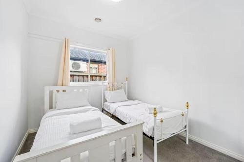 two beds in a white room with a window at Gardenia Serenity & Wellness Retreat in Officer