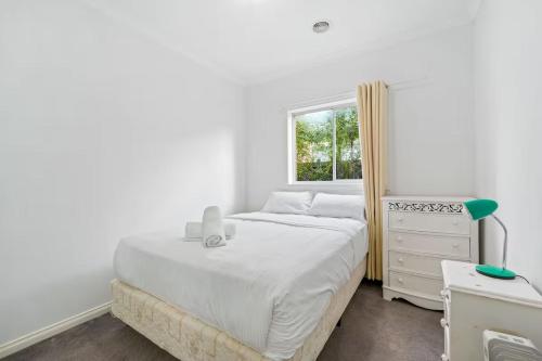a white bedroom with a bed and a window at Gardenia Serenity & Wellness Retreat in Officer