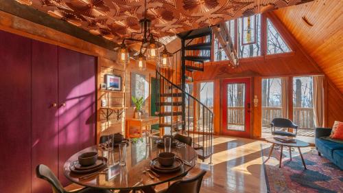 a living room with a table and a spiral staircase at Honeycomb Hideaway by AvantStay Rustic Retreat in Fairview
