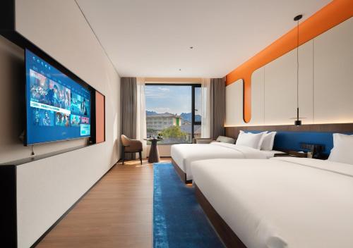 a hotel room with two beds and a flat screen tv at Zhangjiajie Yujie Hotel in Zhangjiajie