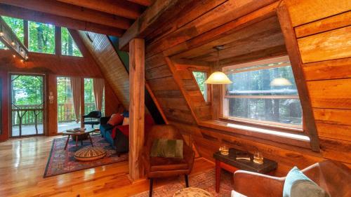 a living room with wooden walls and windows at Honeycomb Hideaway by AvantStay Rustic Retreat in Fairview