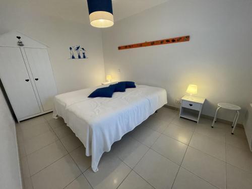 a bedroom with a white bed with blue pillows at Appartement T3 PMR, 2 chambres, jardin privé, plage à pied, parking, internet 4G - FR-1-775-14 in Sarzeau