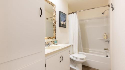 a white bathroom with a toilet and a sink at Sunny by the Sound by AvantStay Coastal Escape in Coupeville