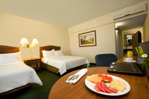 a hotel room with a plate of fruit on a table at Fiesta Inn San Luis Potosi Glorieta Juarez in San Luis Potosí