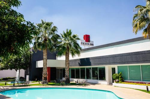 a resort with a swimming pool in front of a building at Fiesta Inn San Luis Potosi Glorieta Juarez in San Luis Potosí