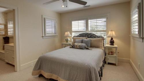 a bedroom with a bed with two night stands and two windows at 3902 Palm Blvd by AvantStay Beach Access Oceanfront Views w Pool in Isle of Palms