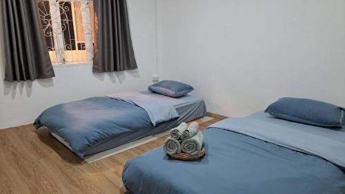 een slaapkamer met 2 bedden met blauwe lakens en een raam bij Kan Haven Homestay in Kanchanaburi