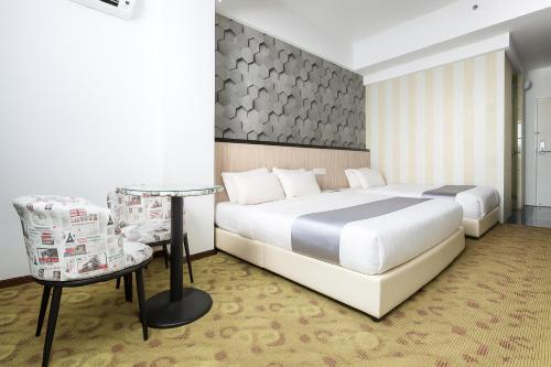 a bedroom with two beds and a table and a chair at THE REED HOTEL MELAKA formerly known as E-Red Hotel Melaka in Melaka