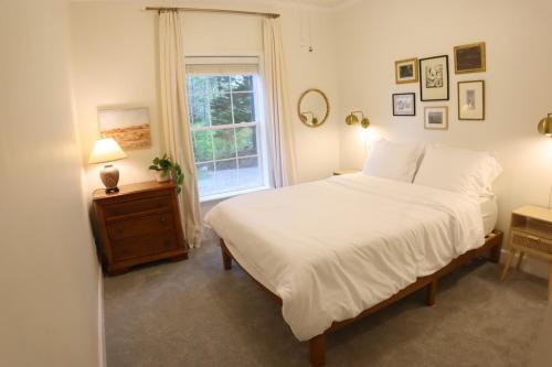 a bedroom with a white bed and a window at The Gentry Hideaway, A Private Mayberry Retreat in Mount Airy