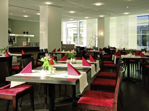 a dining room with tables and chairs with red napkins at ibis Dresden Zentrum in Dresden