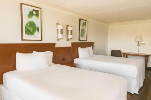 due letti in una camera d'albergo con lenzuola bianche di Horizon Inn Norcross a Norcross