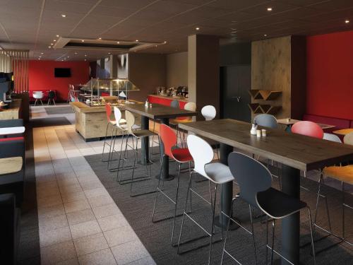 a restaurant with long communal tables and chairs at ibis Nürnberg Hauptbahnhof in Nürnberg