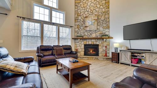 a living room with leather furniture and a stone fireplace at The Nest at Pinecrest by AvantStay Spacious Deck Game Room Fire Pit in Pocono Pines