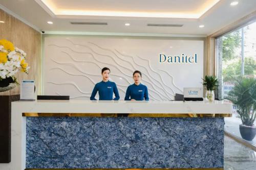 Dos hombres de pie detrás de un mostrador con las palabras negado en Danitel Halong, en Ha Long