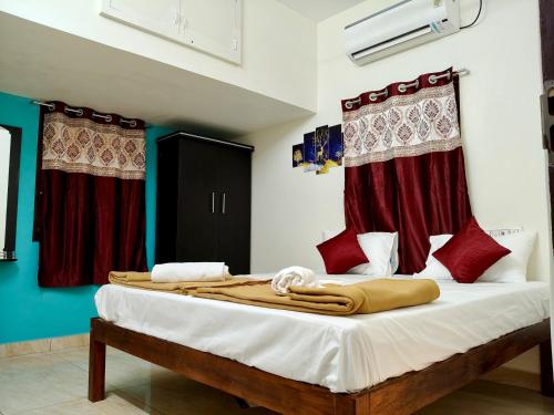 a bedroom with a large bed with red curtains at Kumbha Nivas in Kumbakonam