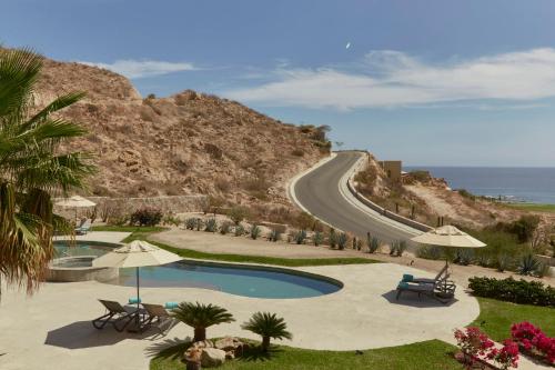 a swimming pool next to a road with a mountain at Live Aqua Private Residences Los Cabos in Cabo San Lucas