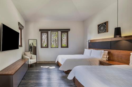 a hotel room with two beds and a flat screen tv at Live Aqua Private Residences Los Cabos in Cabo San Lucas