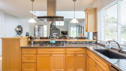 a kitchen with wooden cabinets and a sink at Villa Manzanita by AvantStay Hot Tub 1 Block to BeachTown Chefs Kitchen in Manzanita