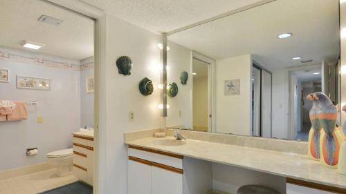 Un baño con lavabo y un espejo grande. en Atlantic Paradise by AvantStay Great Location w Balcony Outdoor Dining Shared Pool Hot Tub, en Key West