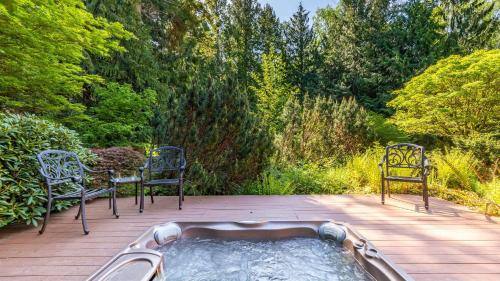 a hot tub on a wooden deck with two chairs at Rhythm Waters by AvantStay Garden Paradise Pond in Langley