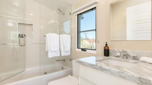 a white bathroom with a tub and a sink and a shower at Sea Crown by AvantStay 5mins from the Beach w Multiple Terraces PermitSLP13639 in Newport Beach
