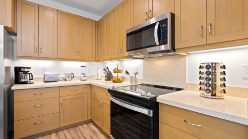 a kitchen with wooden cabinets and a black stove top oven at Mauna View by AvantStay 10min to Beach Backyard in Waianae