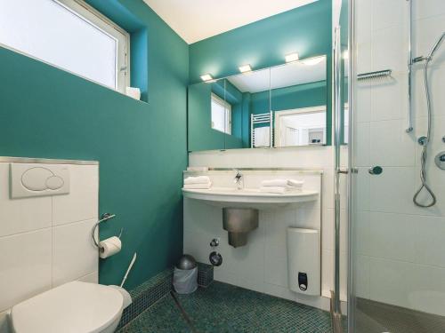 a bathroom with a toilet and a sink and a mirror at Kliffsand-68 in Kampen