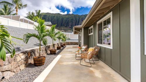 a patio with chairs and palm trees on the side of a house at Oluolu by AvantStay Single-Story Home by Ocean in Waianae