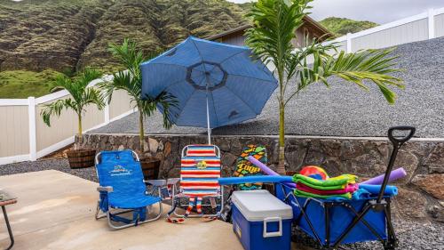 a patio with two chairs and a blue umbrella at Oluolu by AvantStay Single-Story Home by Ocean in Waianae