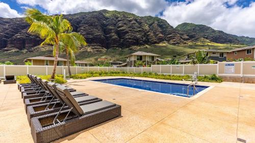 a swimming pool with lounge chairs and a palm tree at Oluolu by AvantStay Single-Story Home by Ocean in Waianae