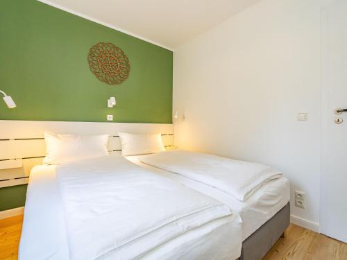 a bedroom with a white bed and a green wall at Haus-Fahnert-2 in Kampen