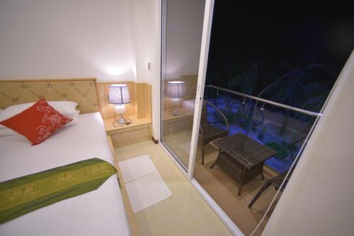 a small room with a bed and a balcony at Hathaa Beach Maldives in Hulhumale